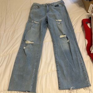 Blue straight leg jeans with rips in the legs.